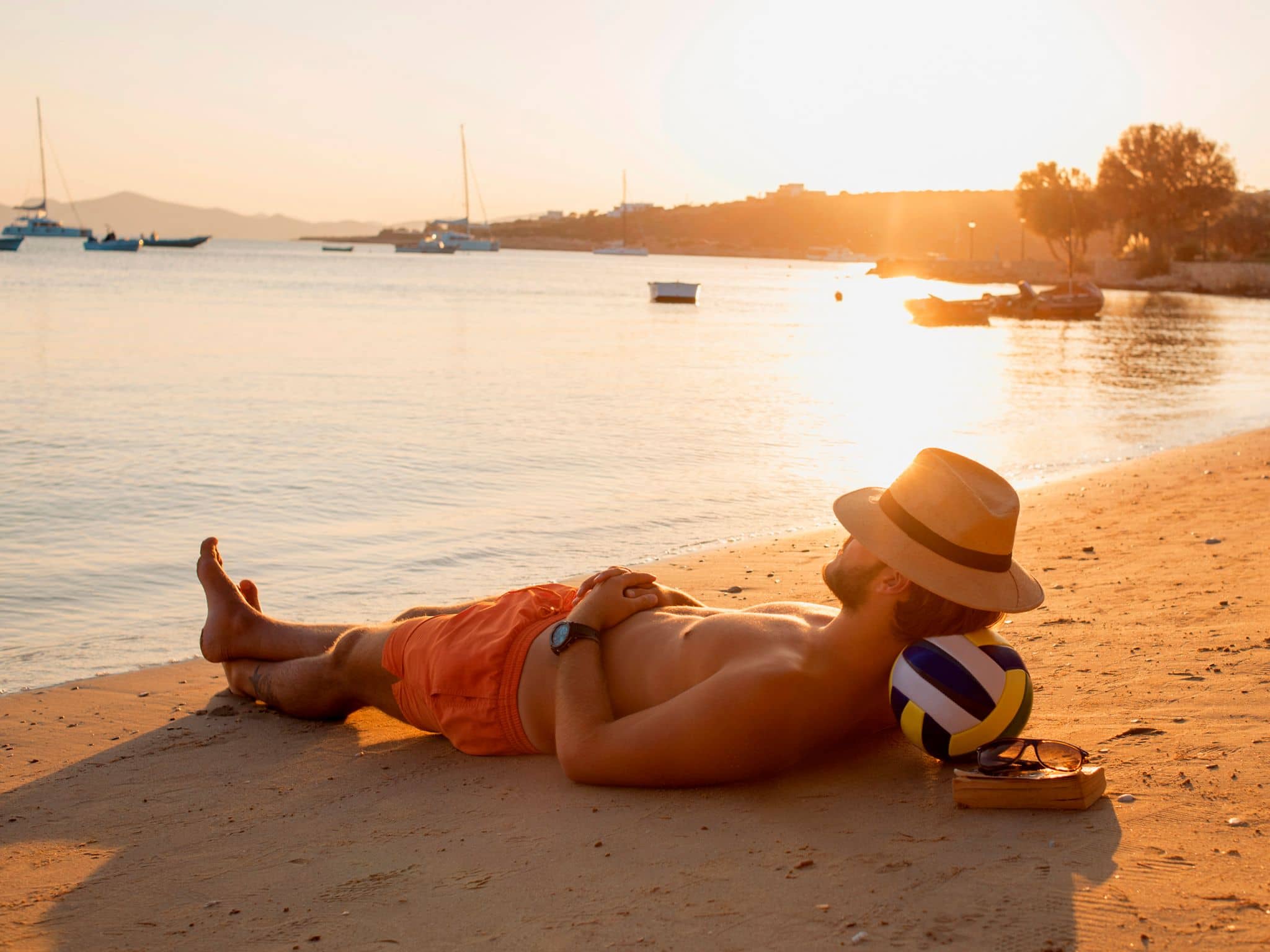 Mann entspannt am Strand in der Abendsonne.