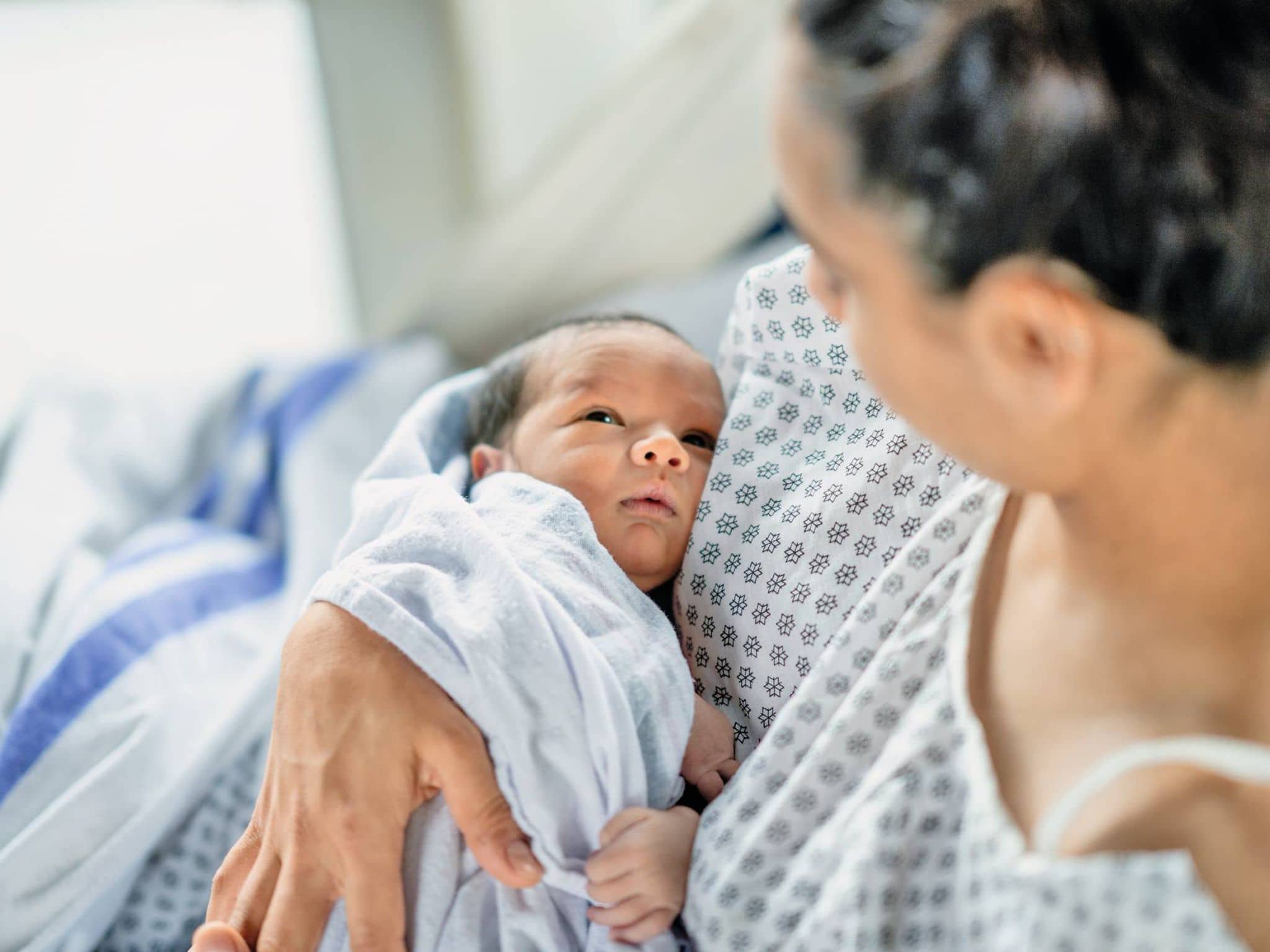 Frau im Geburtskittel mit Baby im Arm