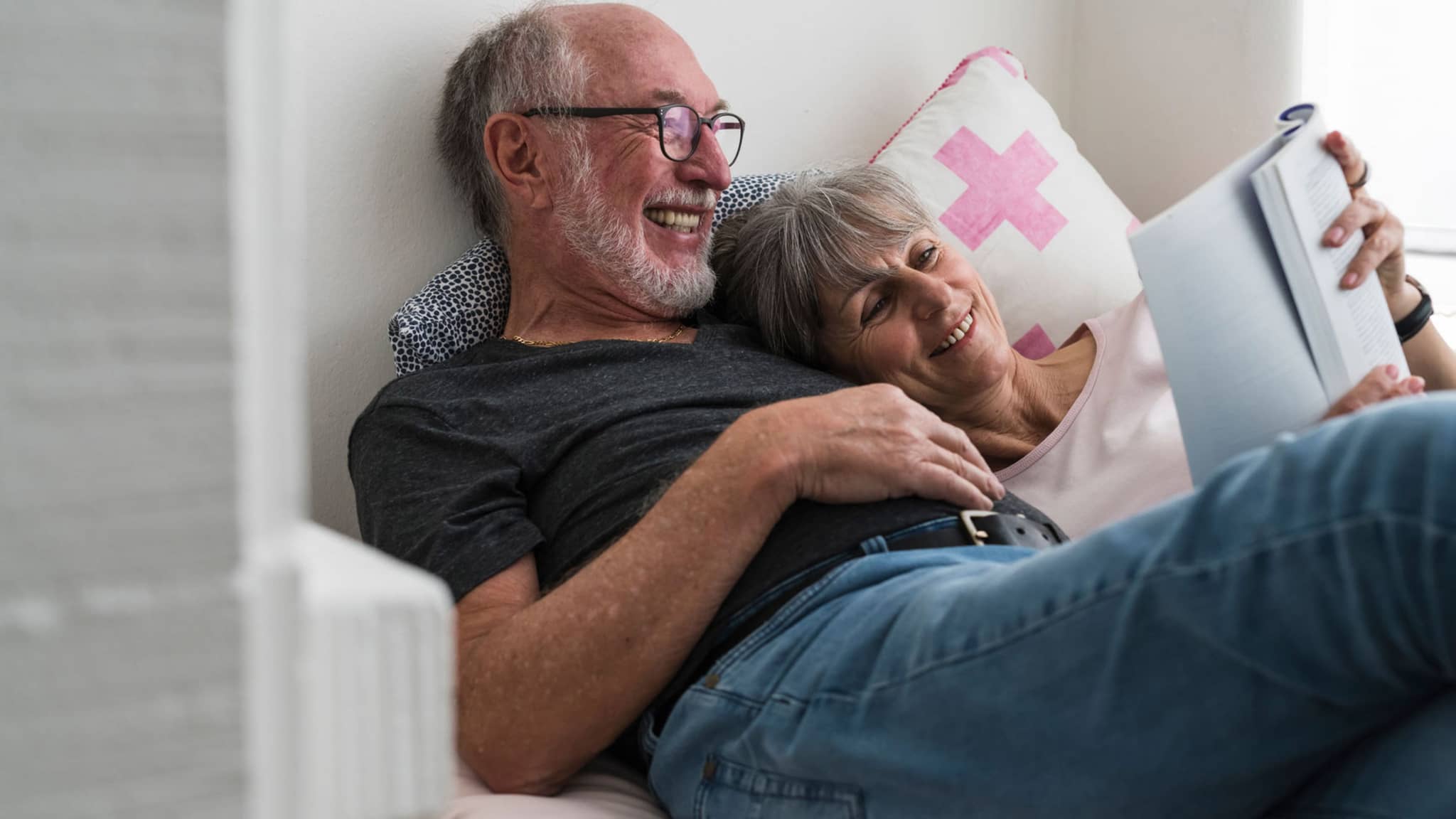 Krebsvorsorge: Glückliches älteres Paar liest gemeinsam ein Buch.