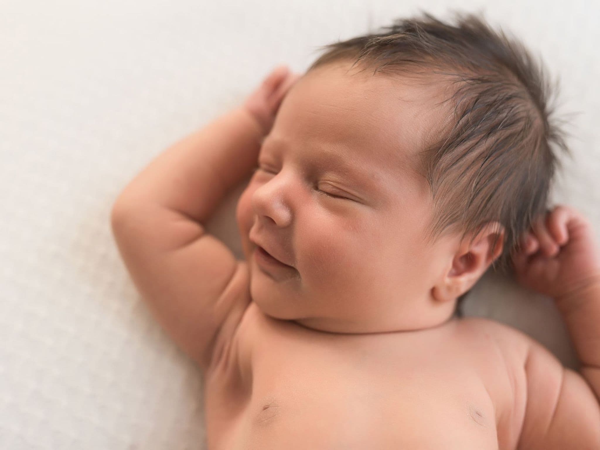 U2 Untersuchung: Ein schwarzhaariges Baby streckt sich im Liegen.