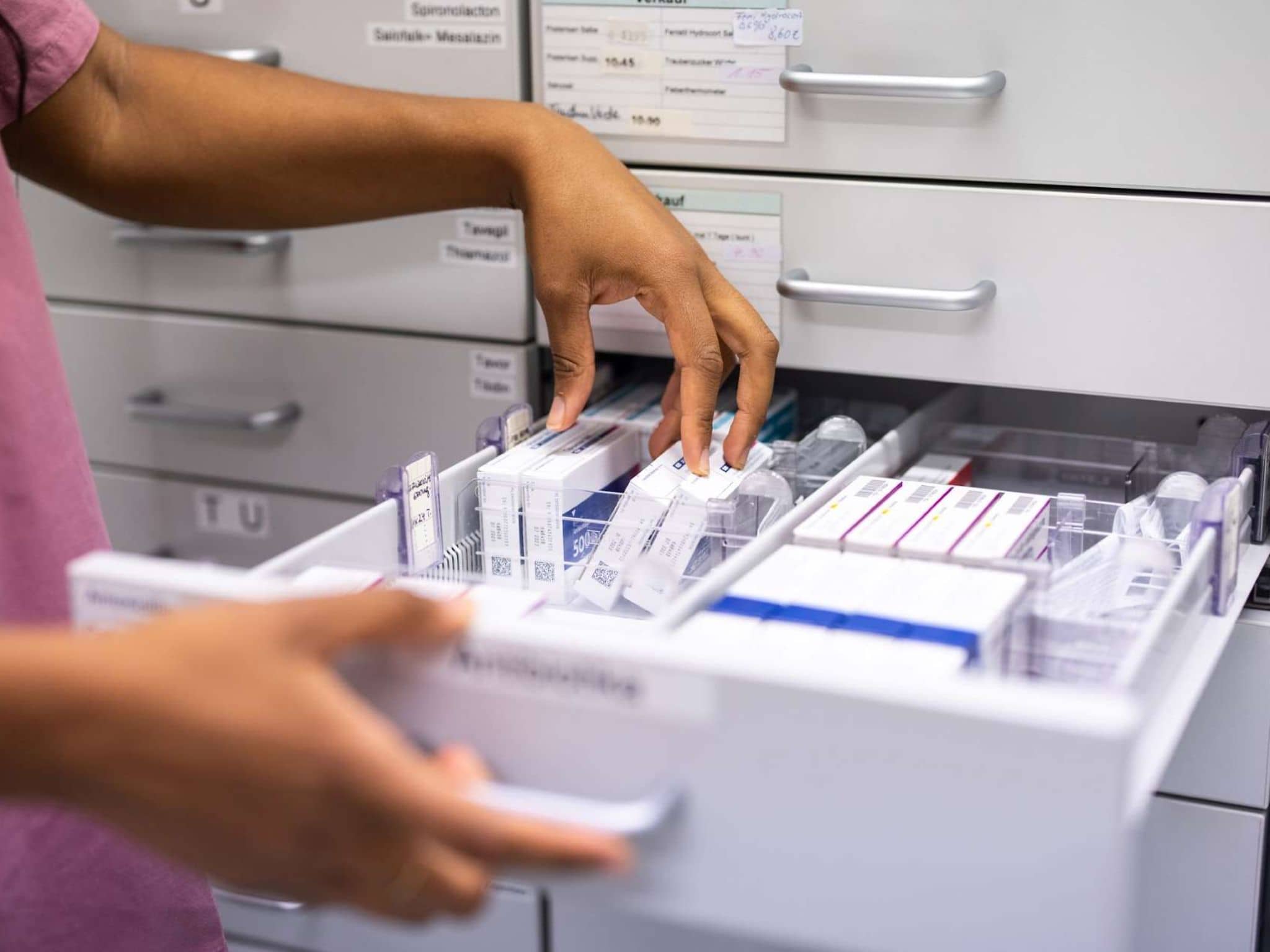 Arzneimittel auf Rabatt: Hände sortieren Medikamente in Schublade.