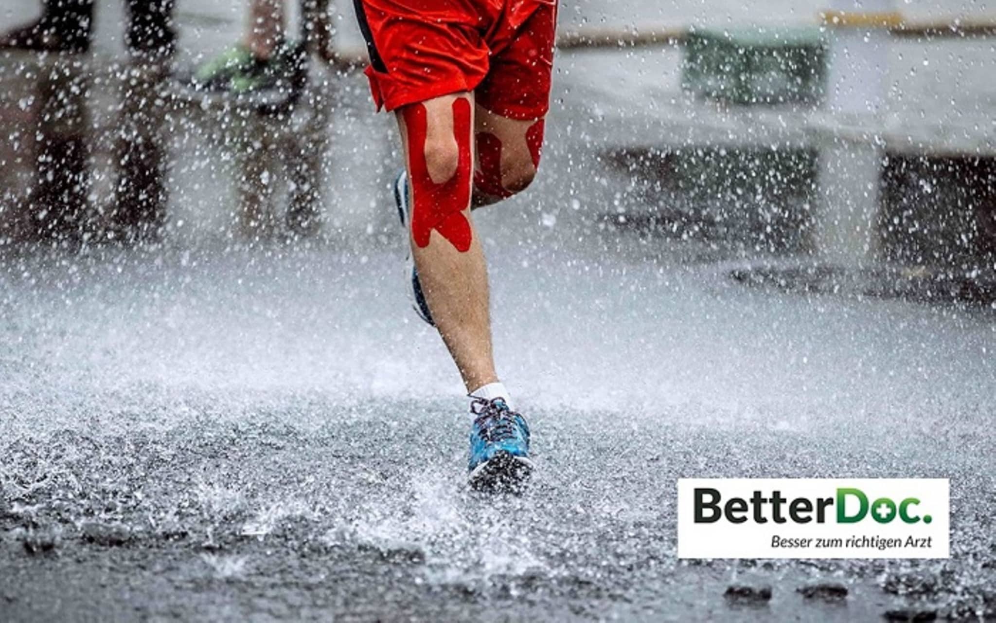 Orthopädische Zweitmeinung: Aufnahme eines Männerbeins, das durch den Regen joggt. Das Knie ist mit Klebestreifen bandagiert.