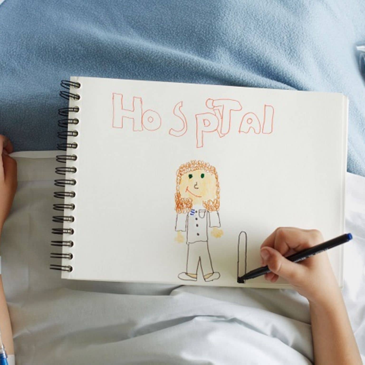 Zweitmeinung: Kind liegt im Krankenhausbett und malt ein Bild.