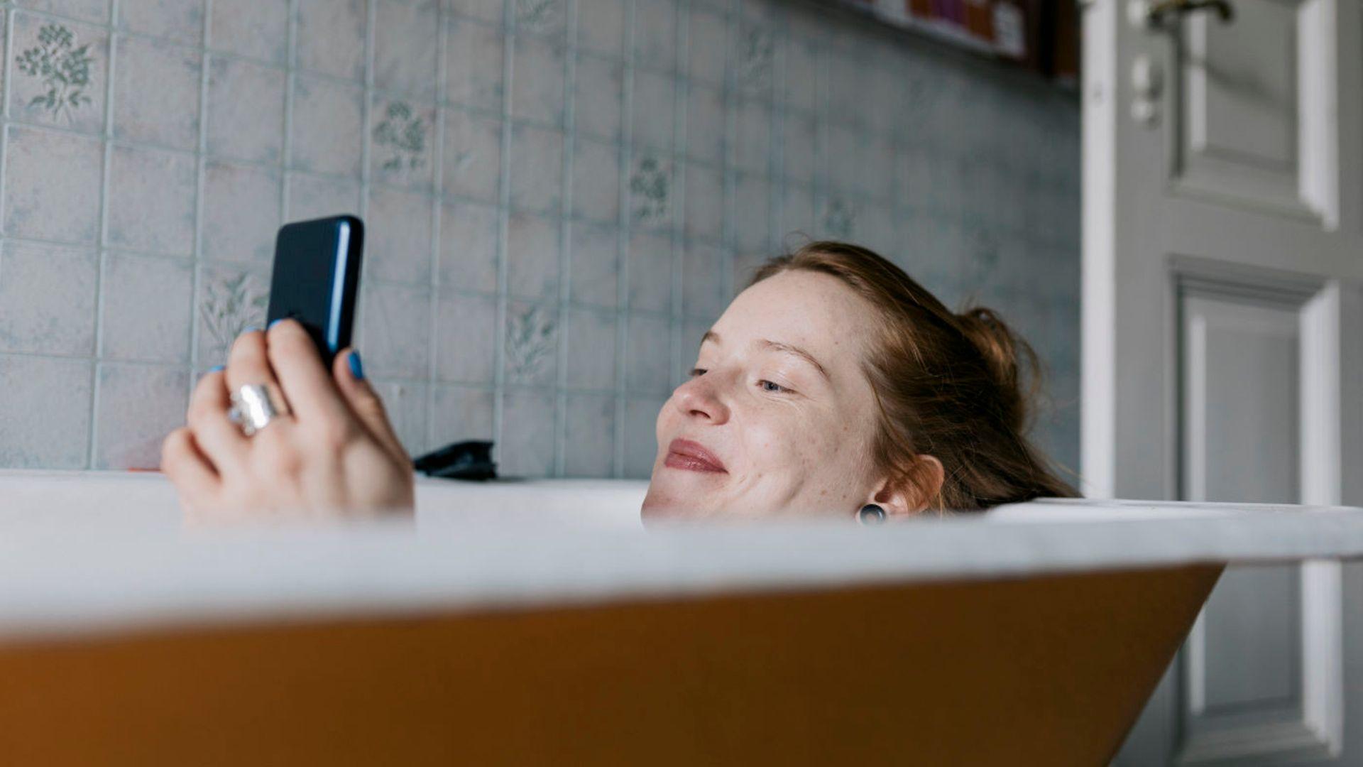 Symbolbild: Frau mit Handy in der Badewanne