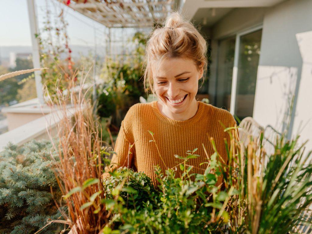 Persönliche Entwicklung: glückliche Frau genießt Pflanzen auf einem Balkon