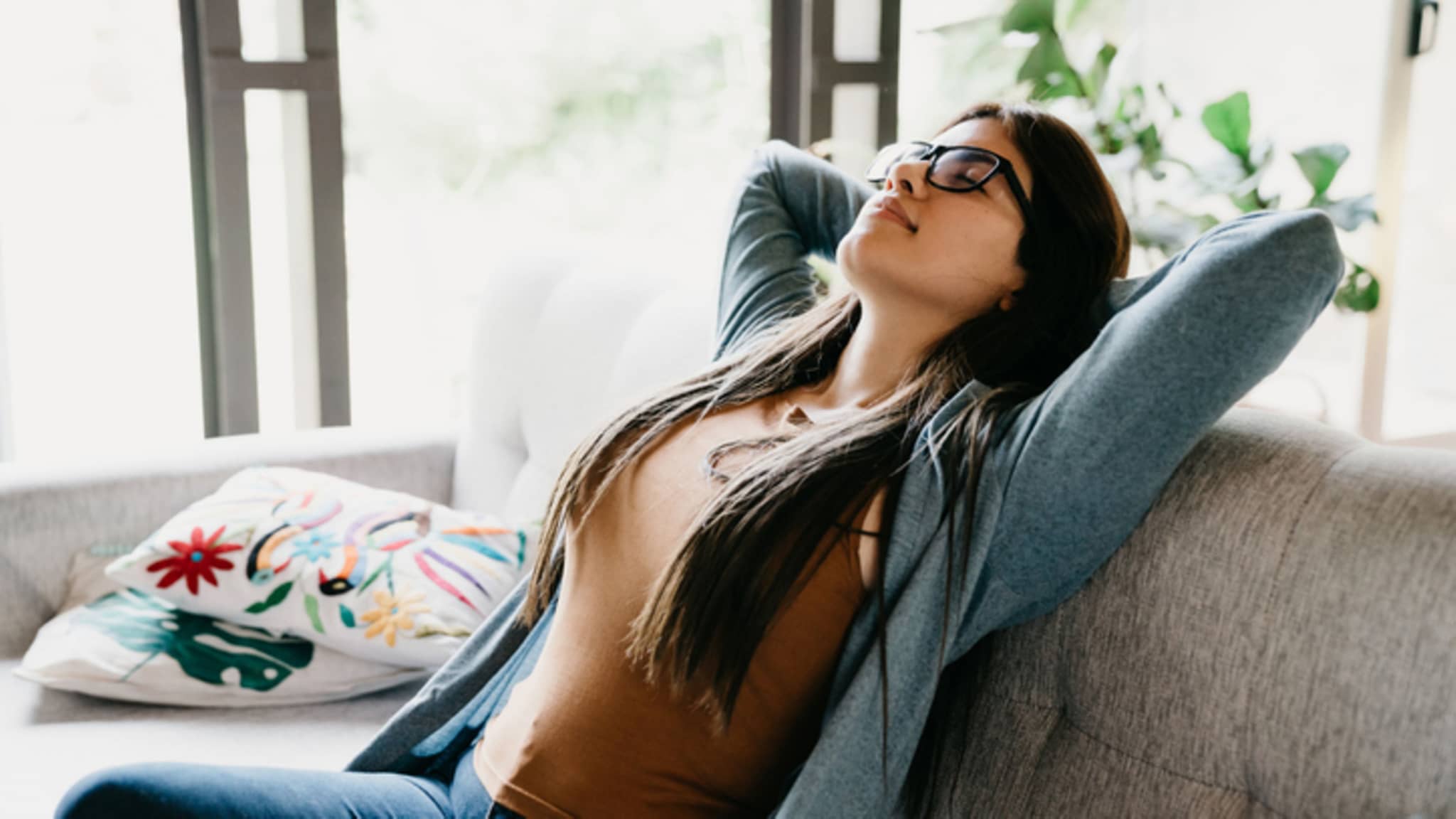 Achtsamkeit: Frau sitzt auf dem Sofa und entspannt sich