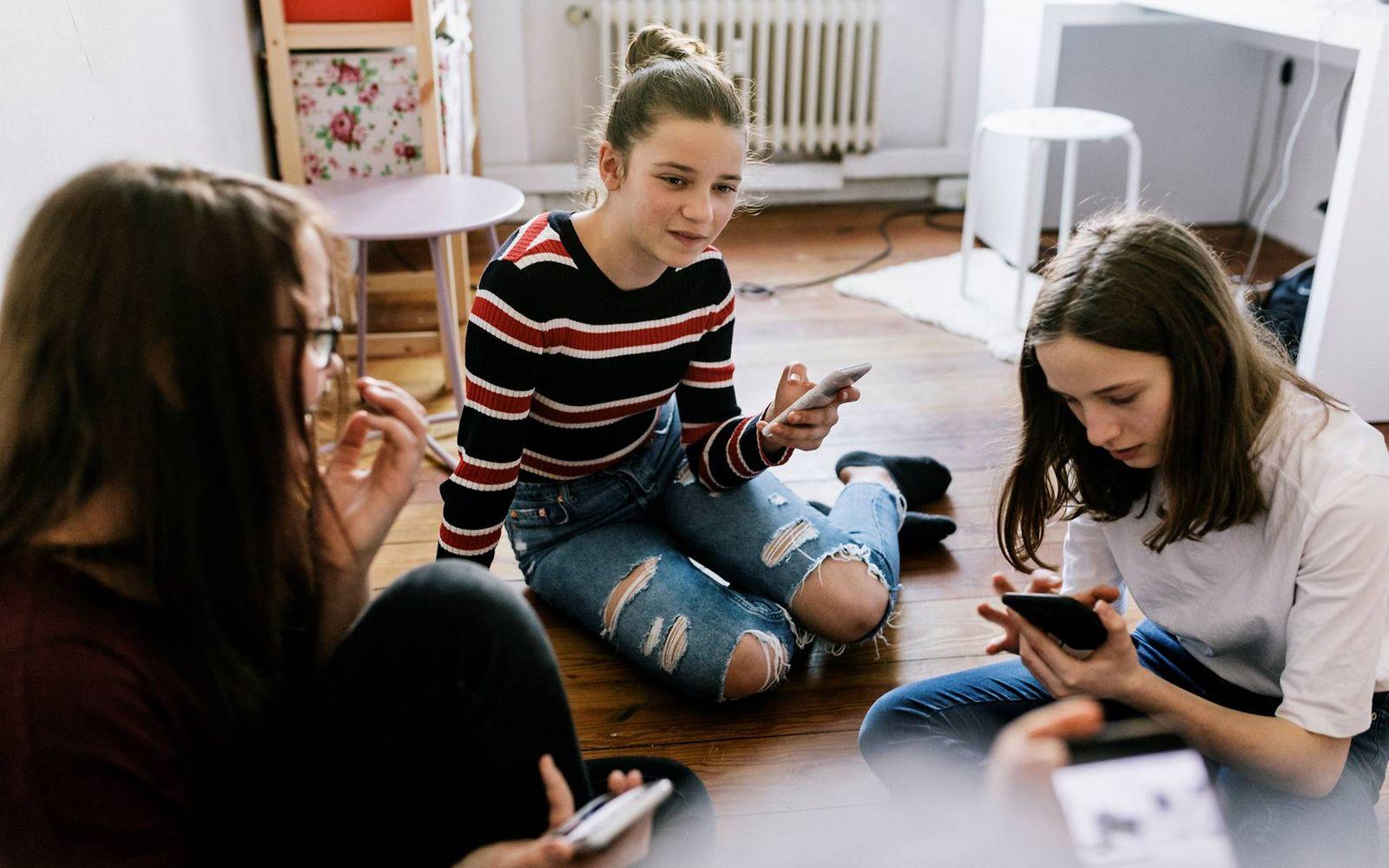 Medienkonsum bei Kindern: Mädchen sitzen mit Smartphones im Schlafzimmer