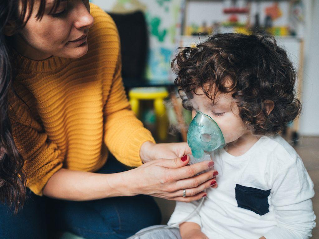 Atemwegserkrankungen bei Kindern: Mutter hilft ihrem Kleinkind mit der Inhalationsmaske