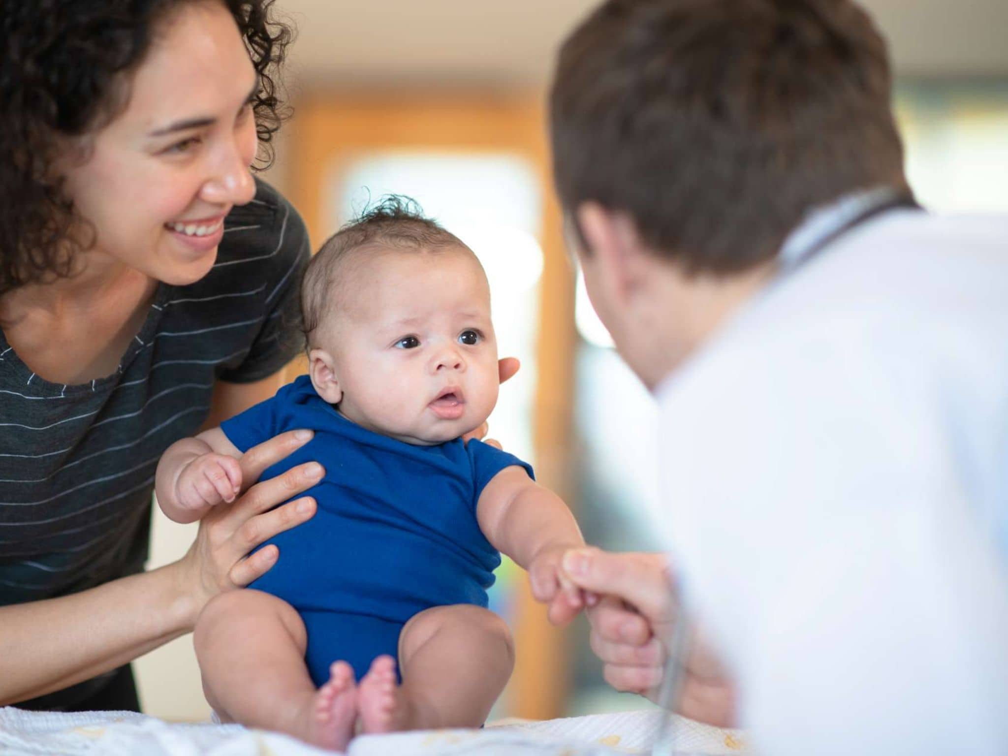 Eine Mutter hält Ihr Baby bei einer Vorsorgeuntersuchung beim Arzt fest.