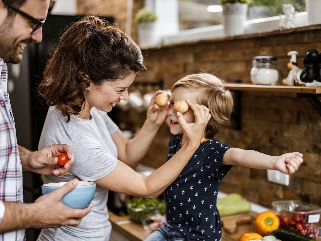 Resistente Stärke: Mutter und Vater spielen mit ihrem kleinen Sohn in der Küche