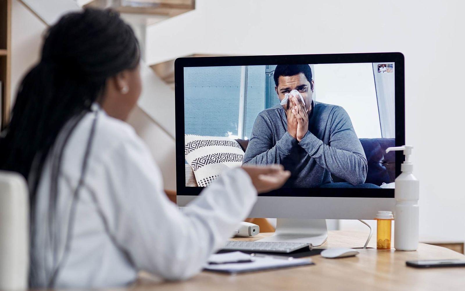 Krankschreibung per Videosprechstunde: Ärztin spricht mit erkälteten Mann auf einem Bildschirm.