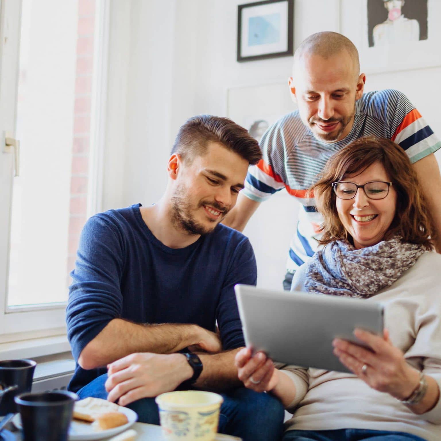 Bild: Frau und zwei Männer schauen auf ein Tablet, auf dem die Selbstlernkurse sind.