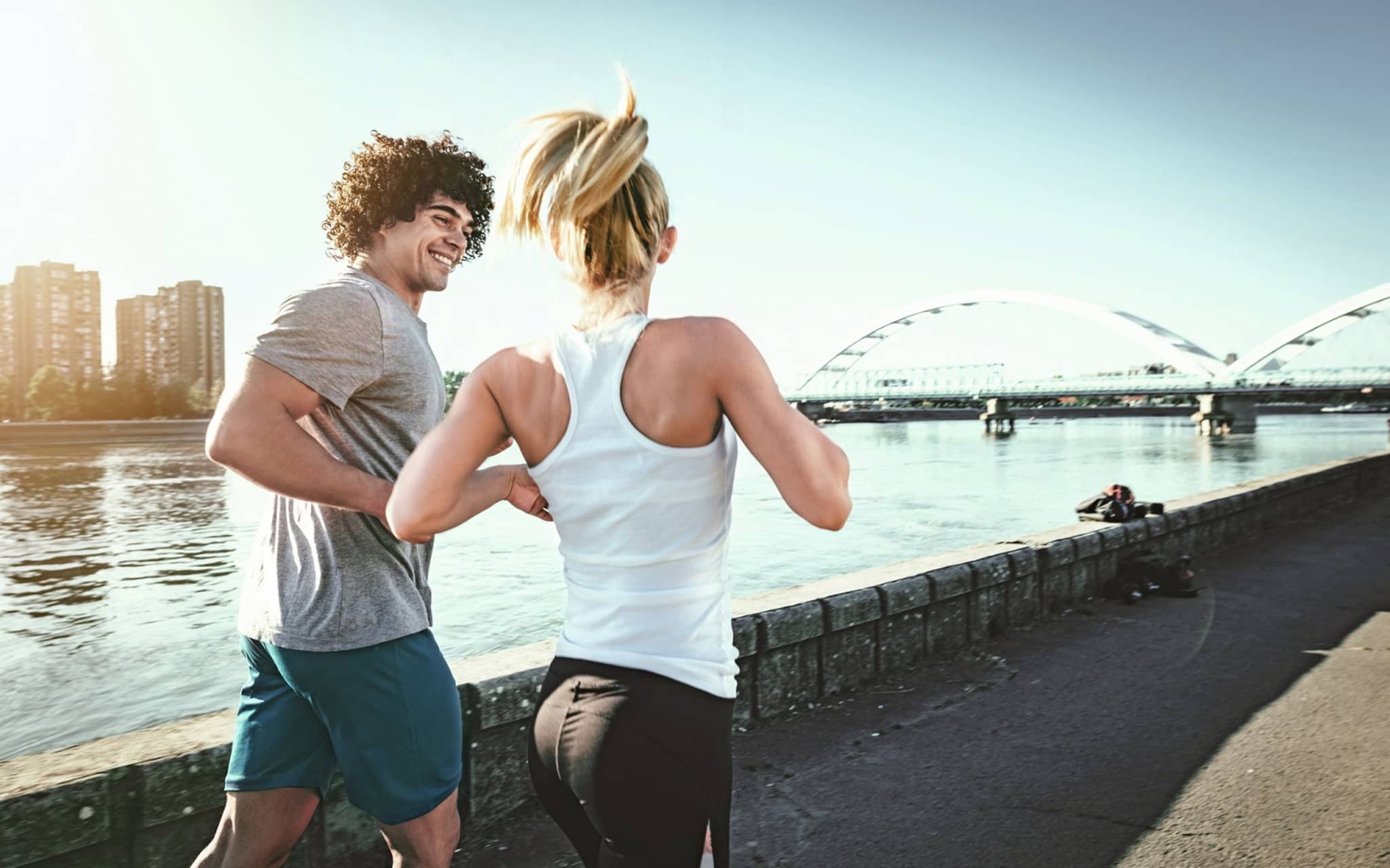 Bild: Mann und Frau joggen an einem Flussufer entlang.