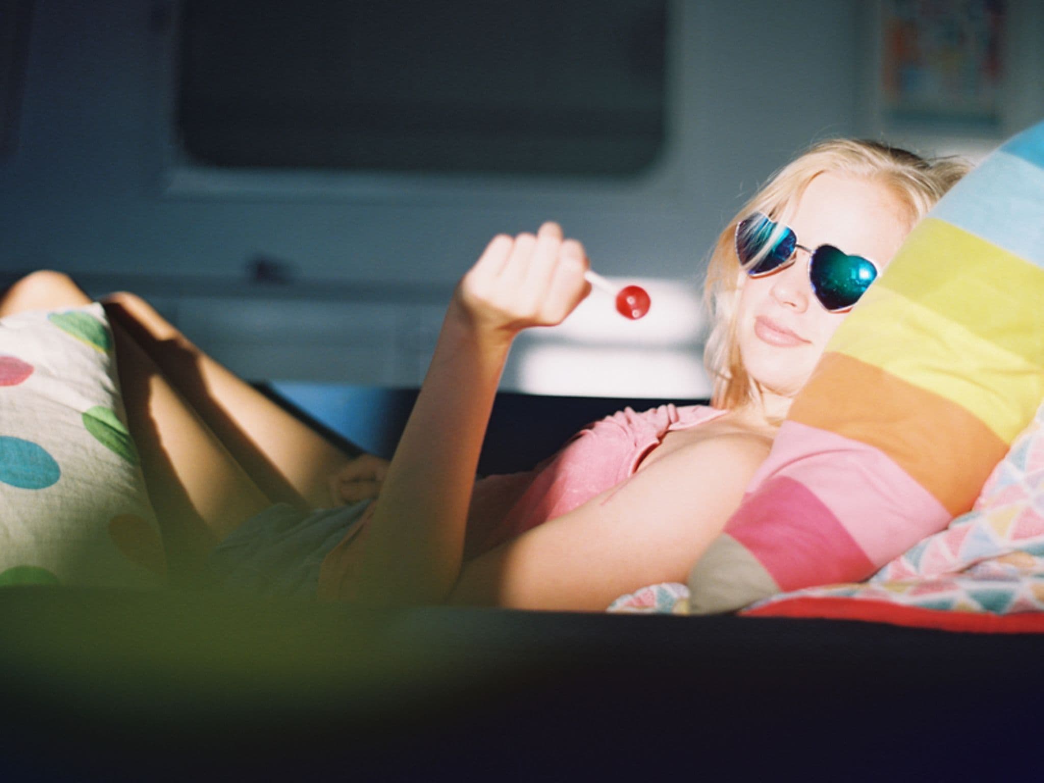 Eine Jugendliche liegt mit Lolly im Bett und hat PMS-Symptome.