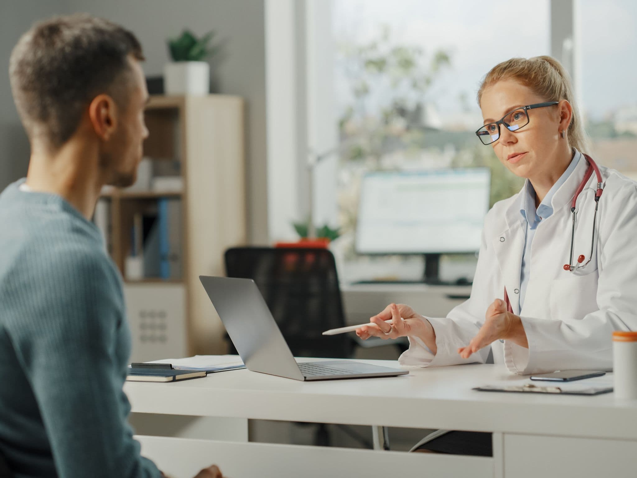 Was macht ein Urologe: Ein junger Mann sitzt im Behandlungszimmer einer Urologin und spricht mit ihr