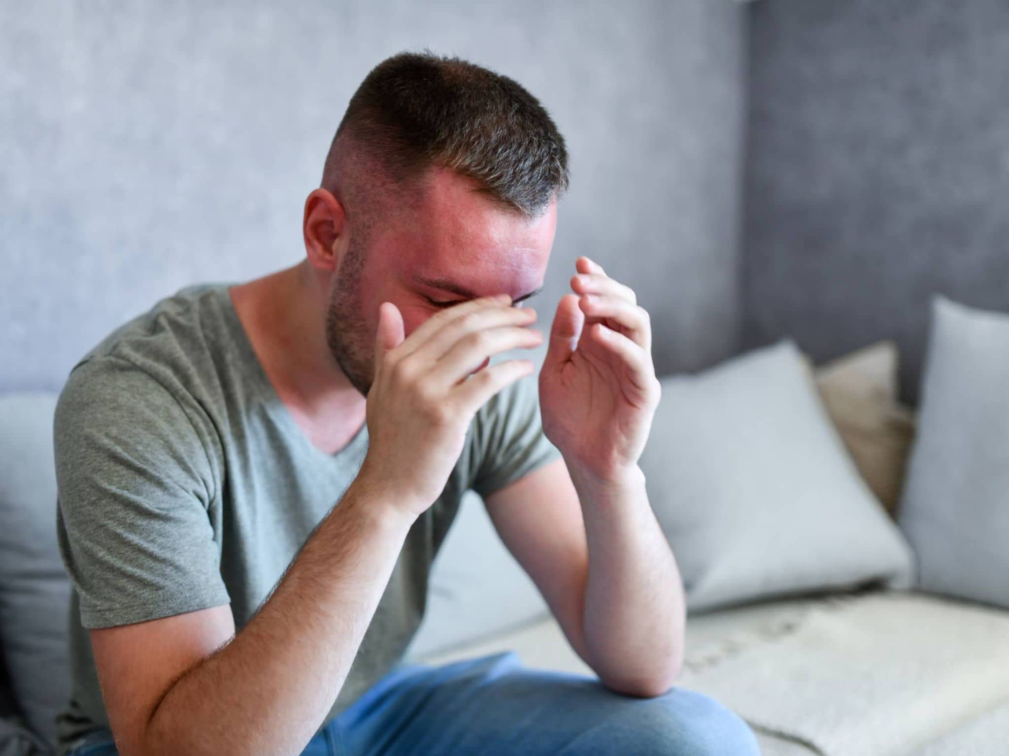 Hitzschlag: Mann sitzt mit hochrotem Kopf auf dem Sofa