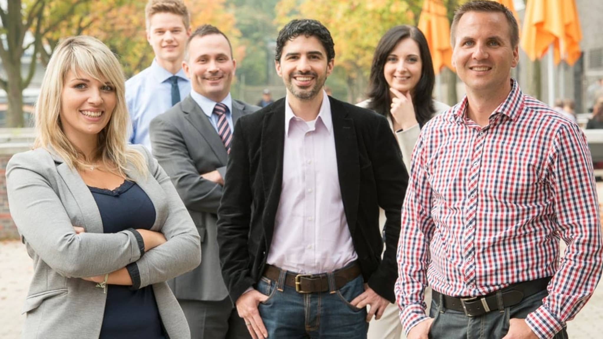 Mitarbeitende der DAK-Gesundheit lächeln stehend in die Kamera.