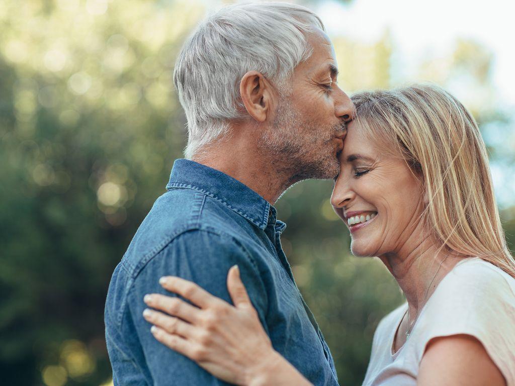 Älter werden: Ein senoriger Mann küsst einer Frau auf die Stirn