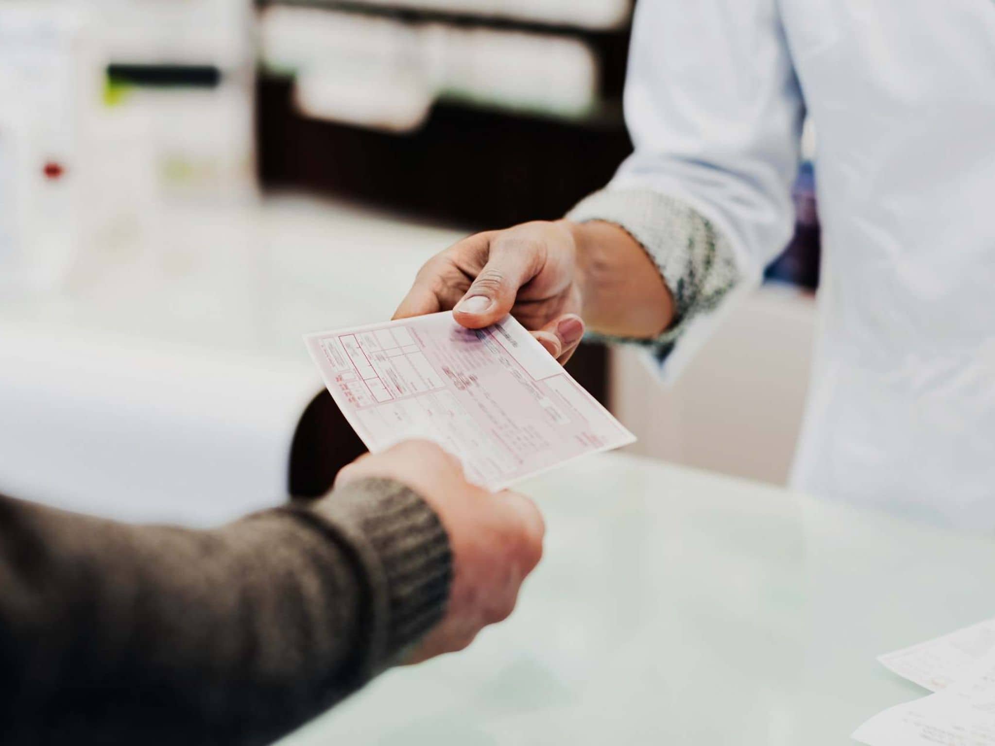 Bild: Kunde gibt Rezept an Apothekerin