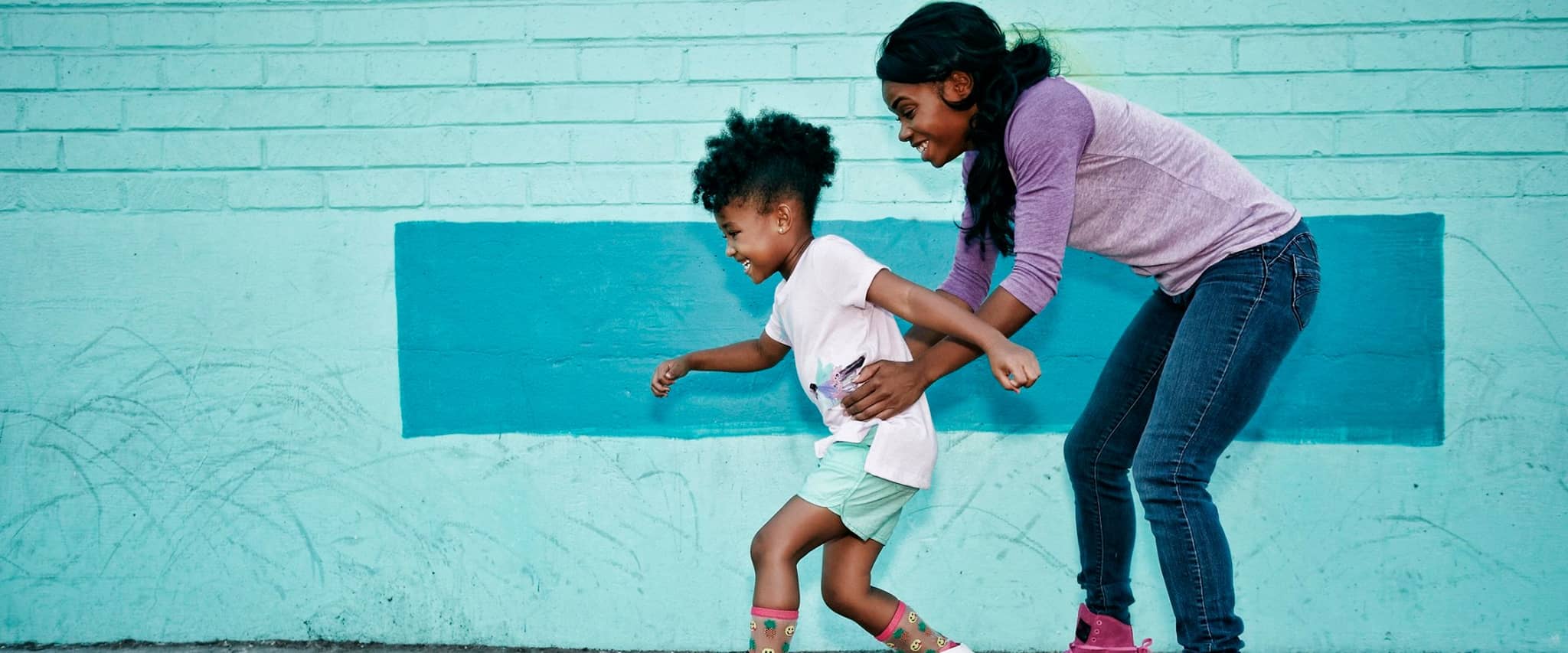 DAK AktivBonus: Frau stützt ihr Kind beim Rollschuhfahren