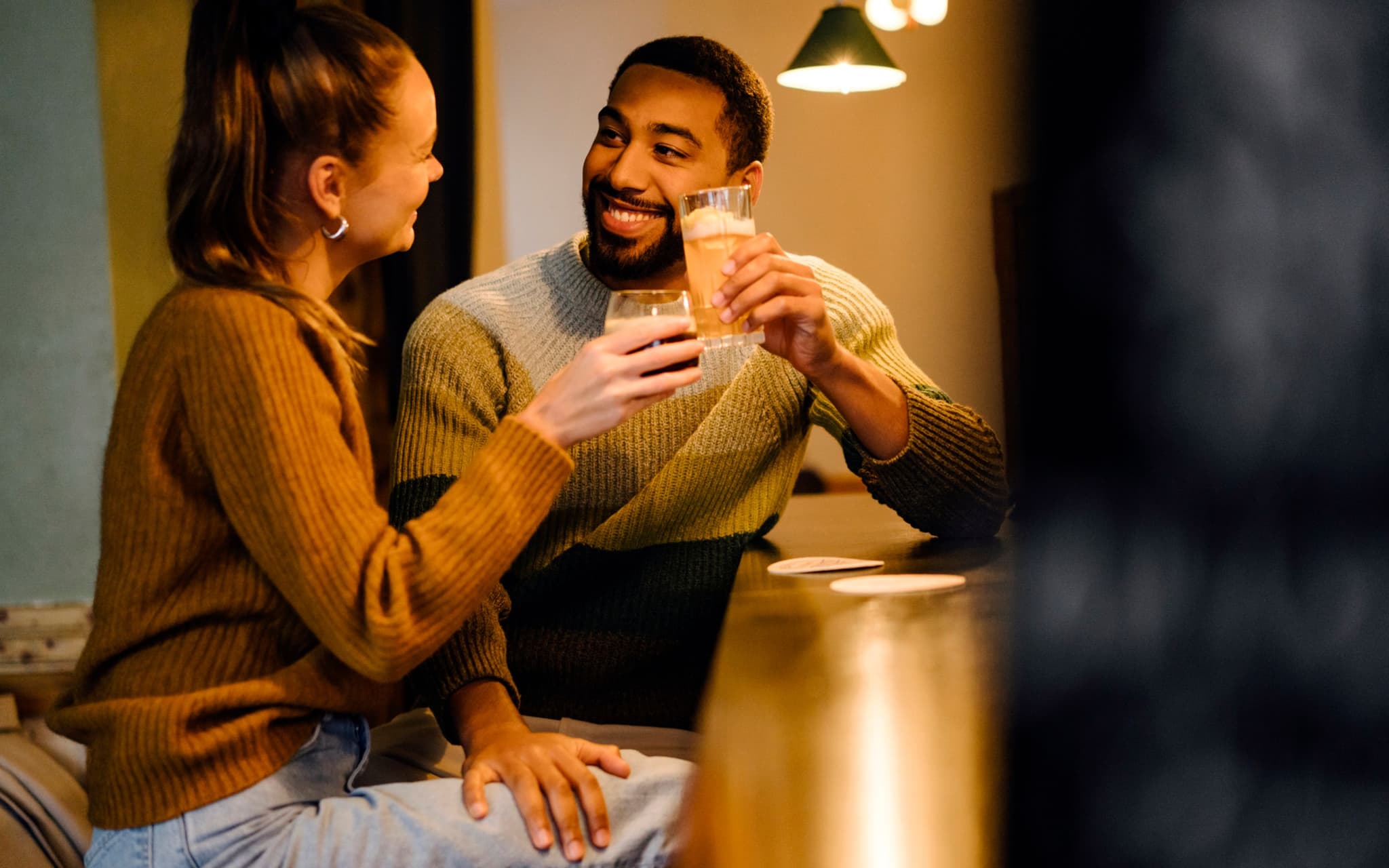 Körpersprache des Flirtens: Ein Mann flirtet mit einer jungen Frau und legt seine Hand auf ihren Oberschenkel