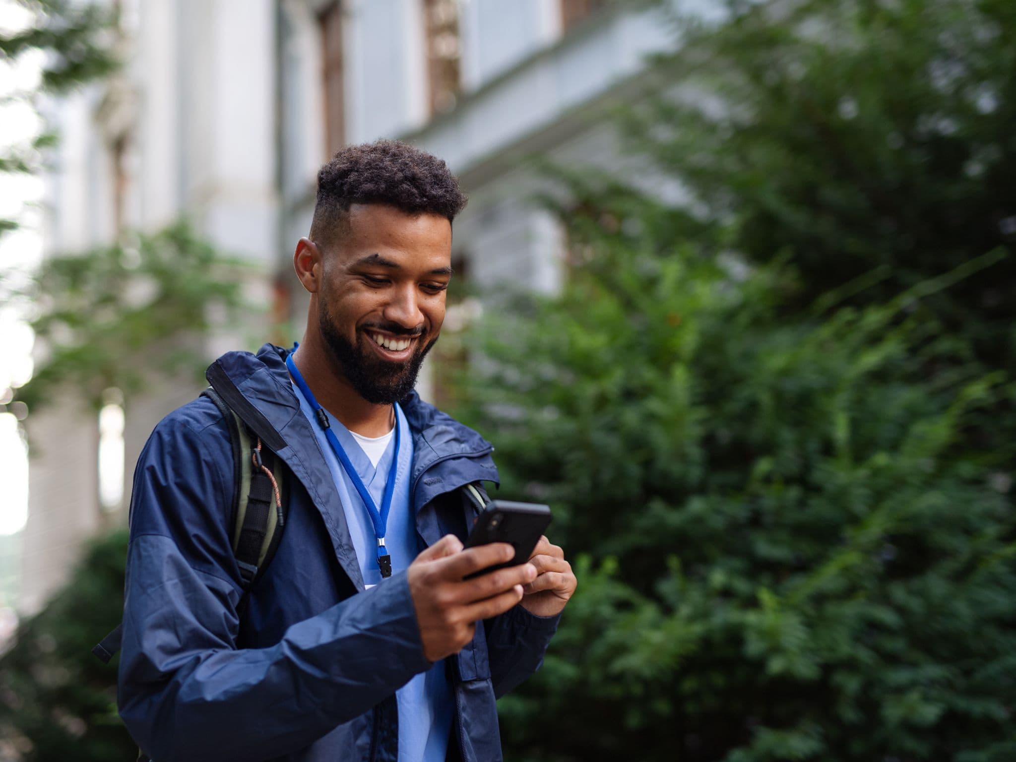DAK App: Man outdoors in street using a phone, smiling.