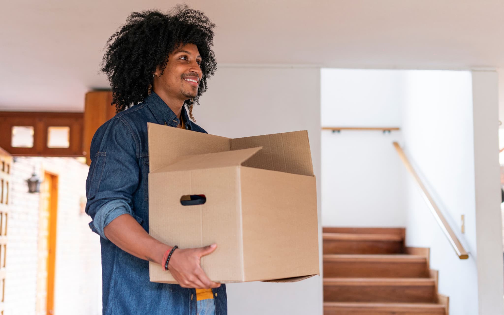 Young man is very happy entering his new house with boxes.