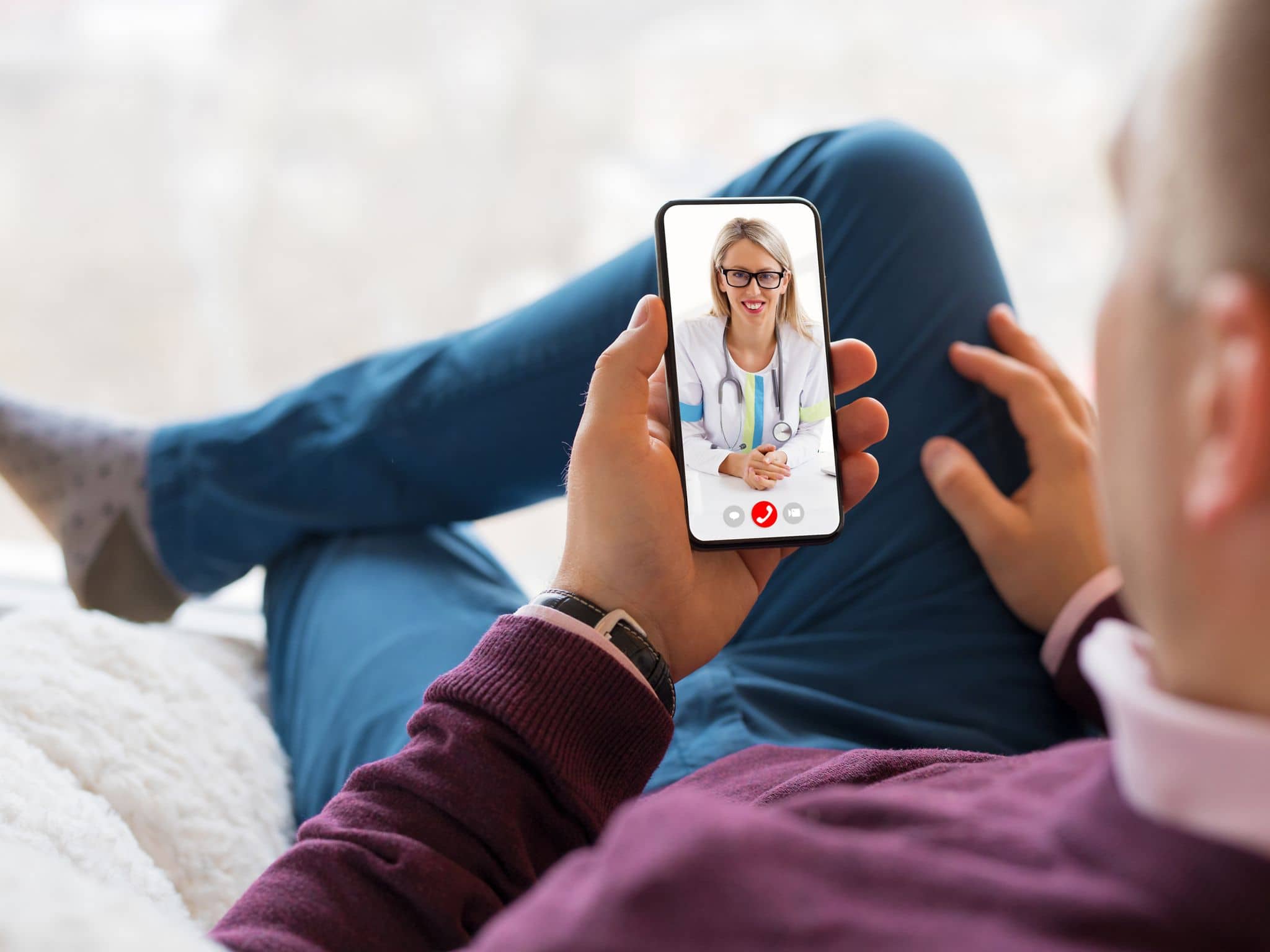 Zweitmeinung Tumorerkrankungen: Mann sitzt auf der Couch und videotelefoniert mit Ärztin