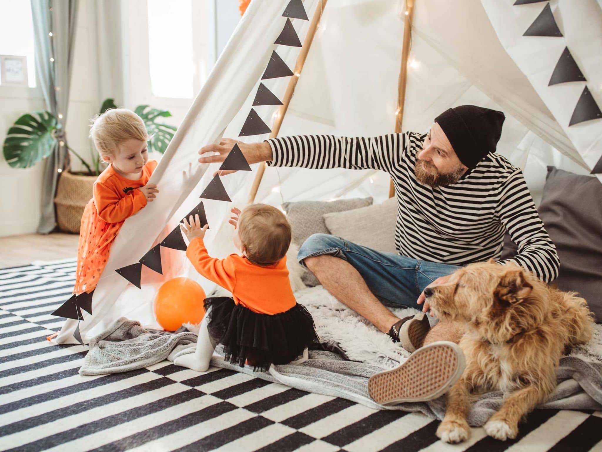 Vater spielt mit seinen Kindern zuhause in einem Zelt.