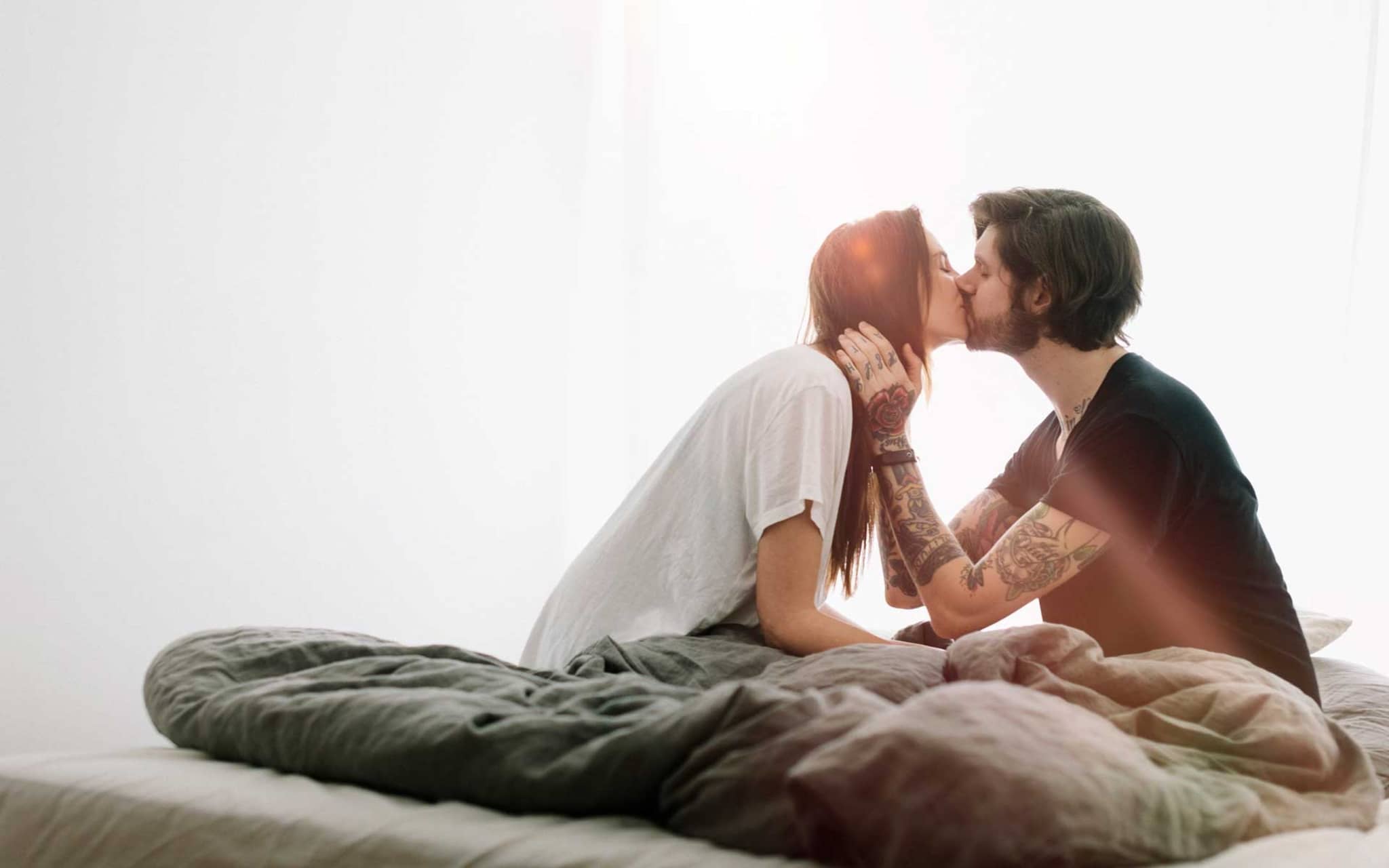 Symbolbild Pille danach: Junges Paar küsst sich im Bett