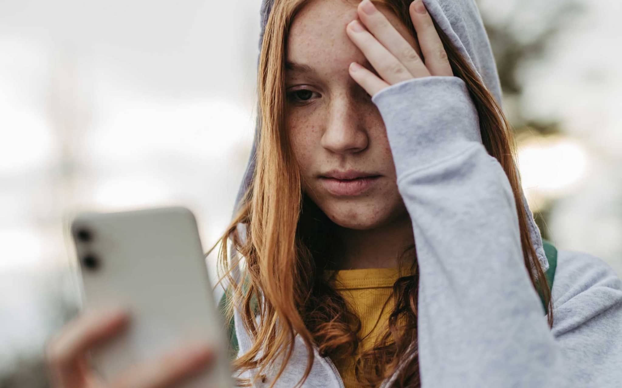 Symbolbild Cybermobbing: Mädchen guckt besorgt auf ihr Smartphone