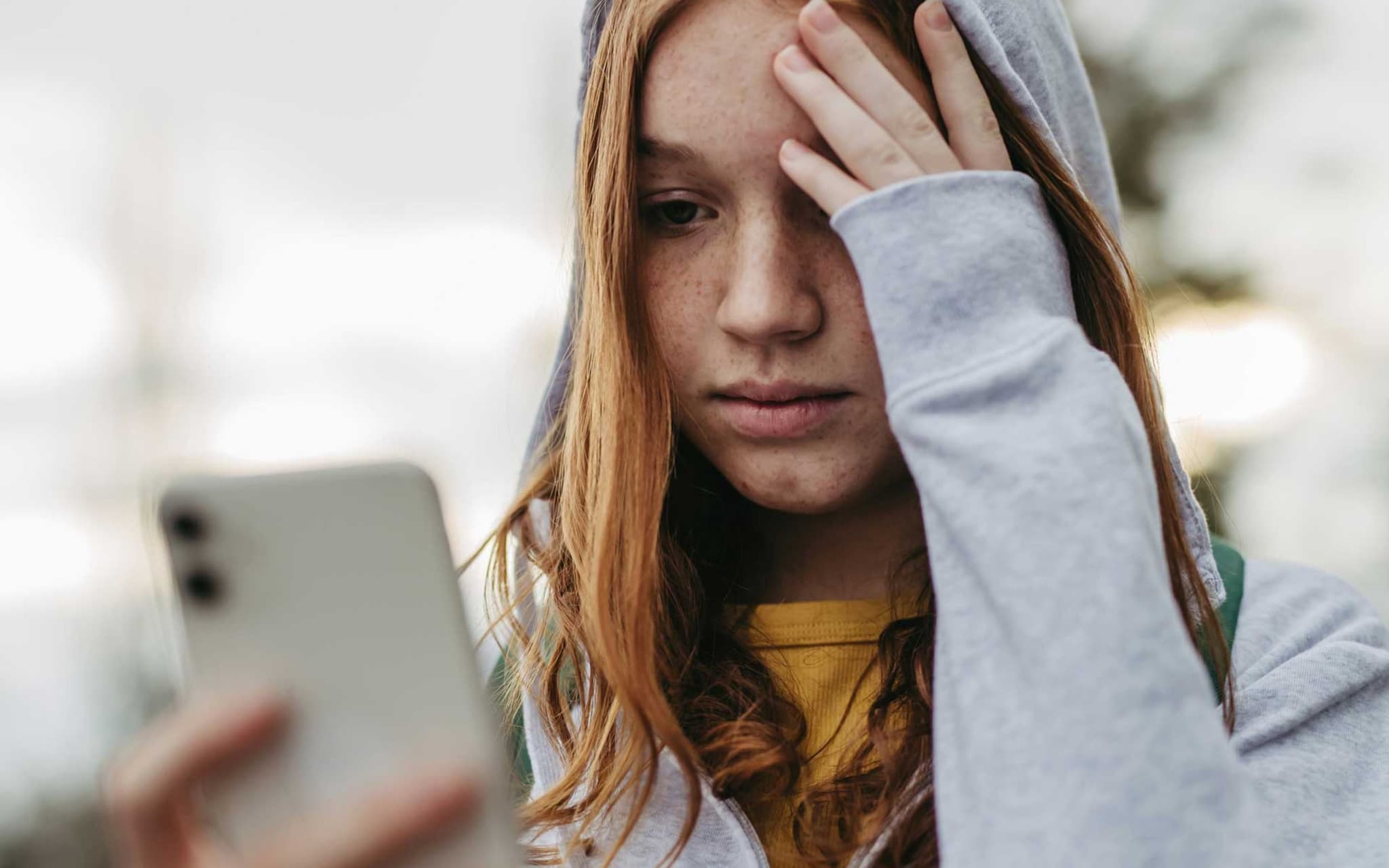Symbolbild Cybermobbing: Mädchen guckt besorgt auf ihr Smartphone
