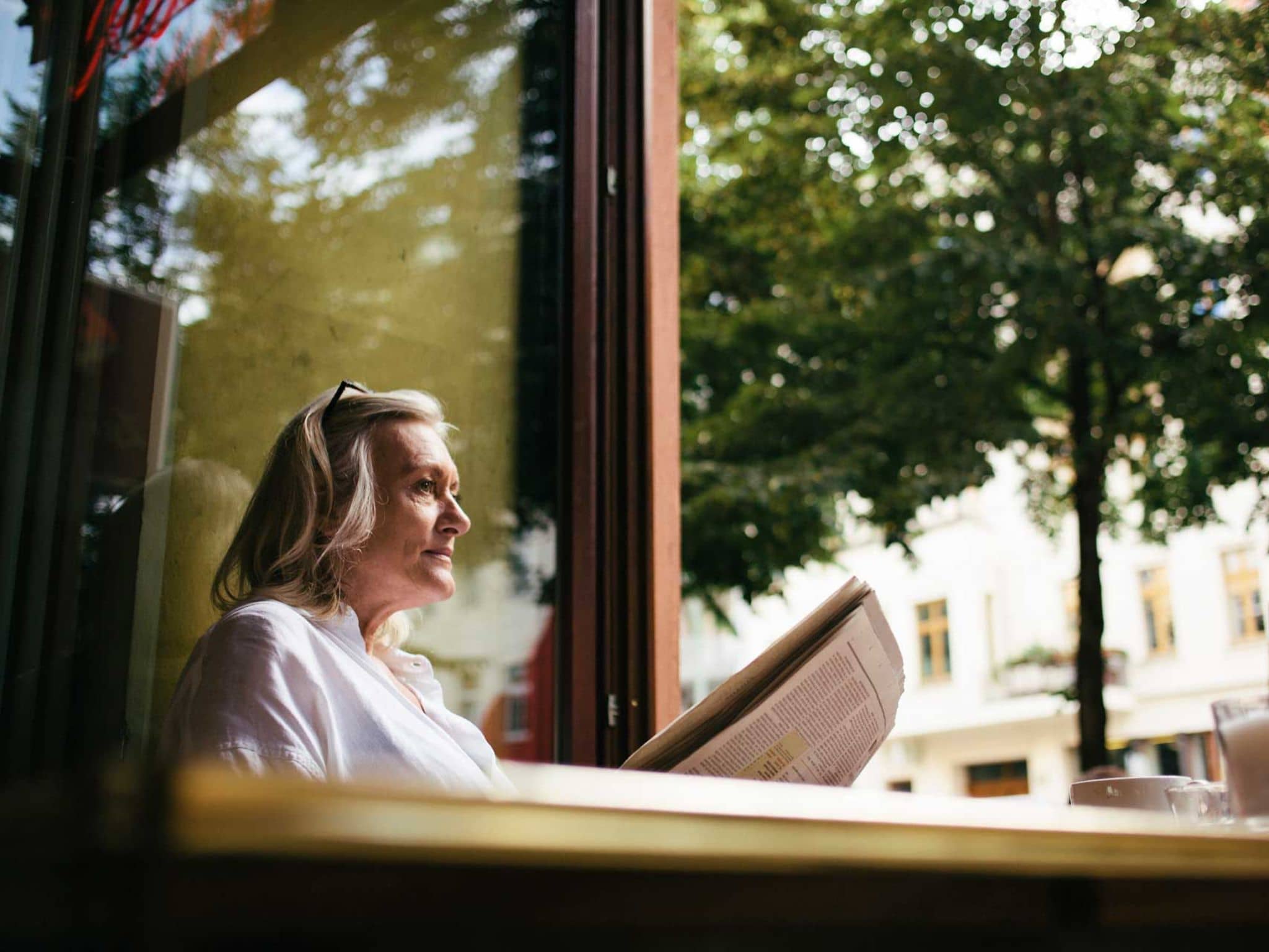 Symbolbild Exazerbation bei COPD: Frau sitzt allein in einem Café