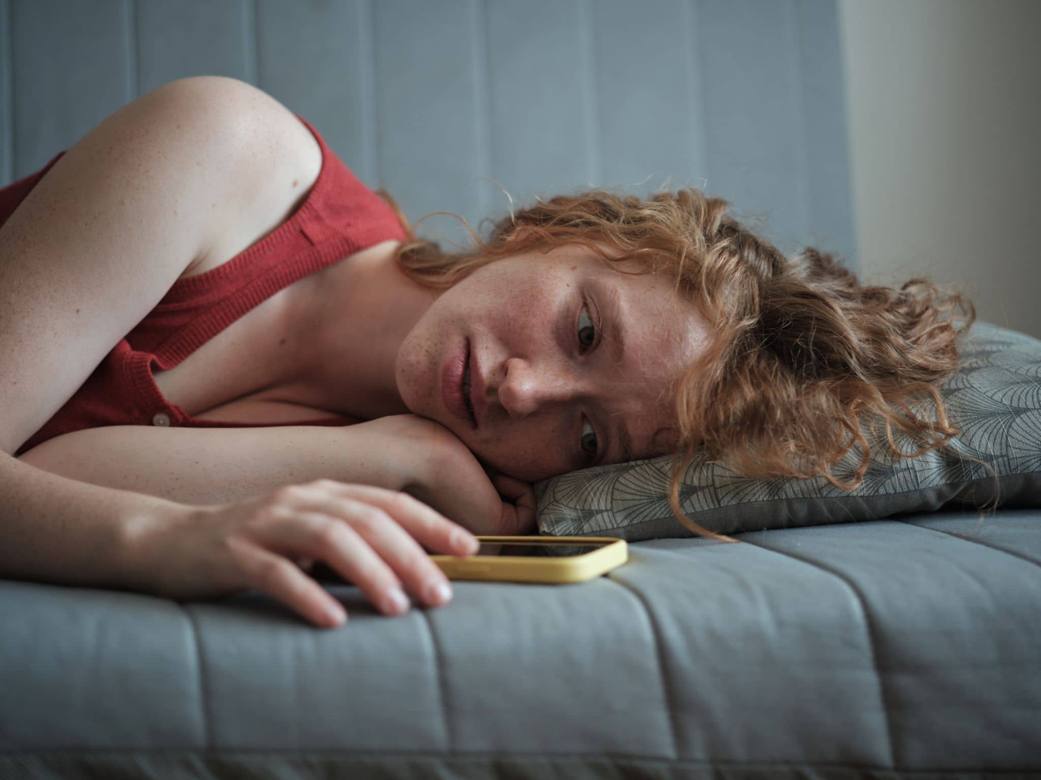 Symbolbild für Liebeskummer: Ein junges Mädchen schaut auf ihr Handy uns ist traurig