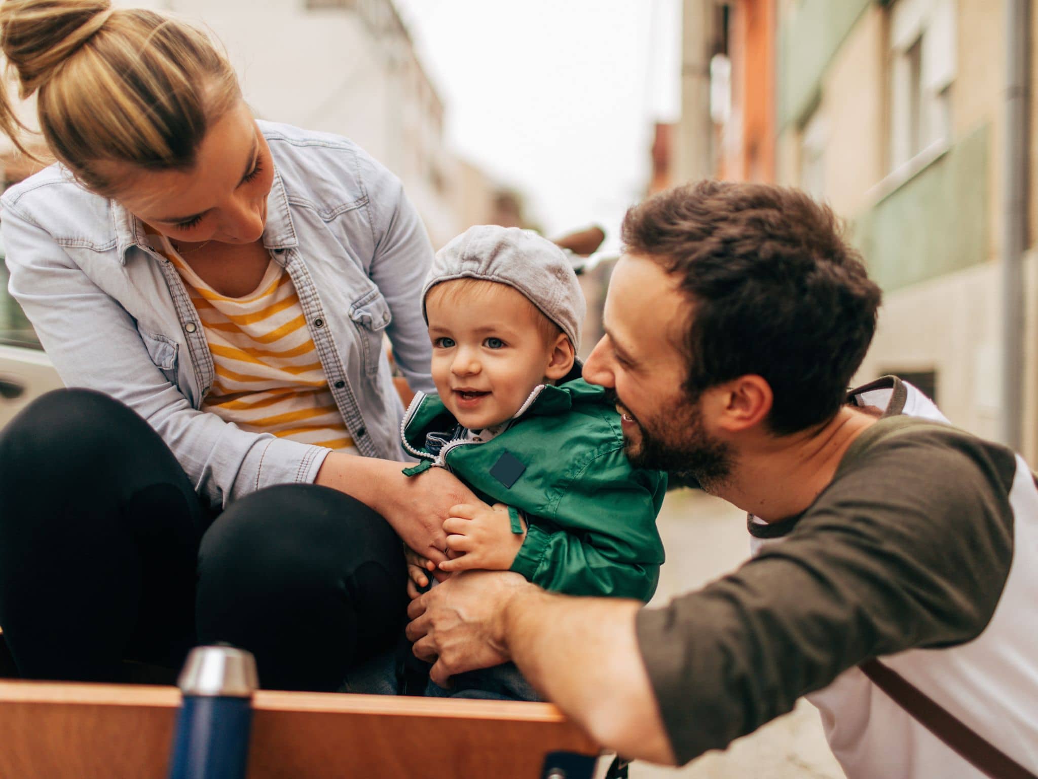 Slika: Mladi par srećno gleda u svoje malo dete.