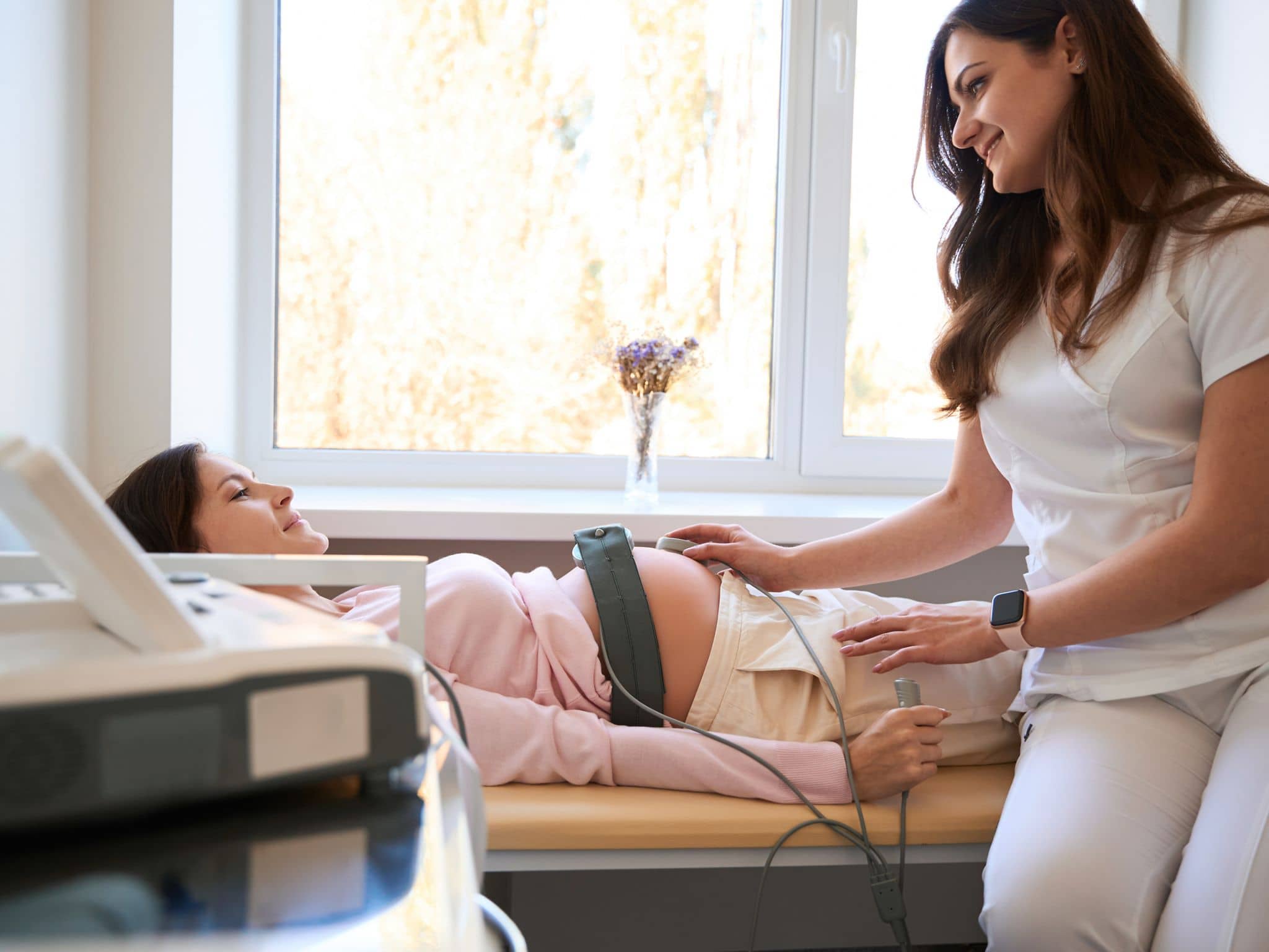 CTG-Wehenschreiber: Eine Schwangere liegt auf einer Liege und bekommt ein CTG