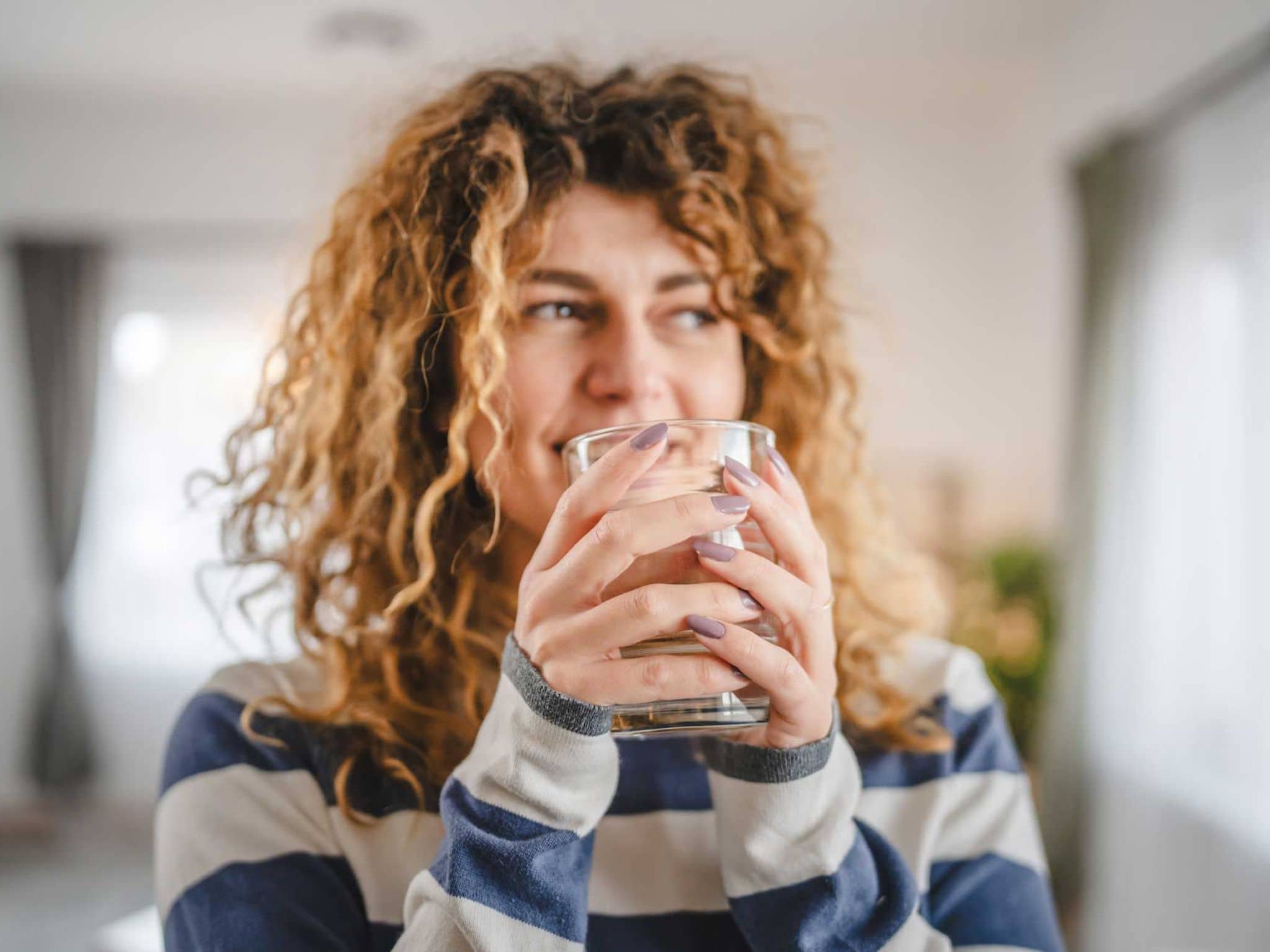 Abnehmen mit Wasser: Junge Frau hält Wasserglas in der Hand