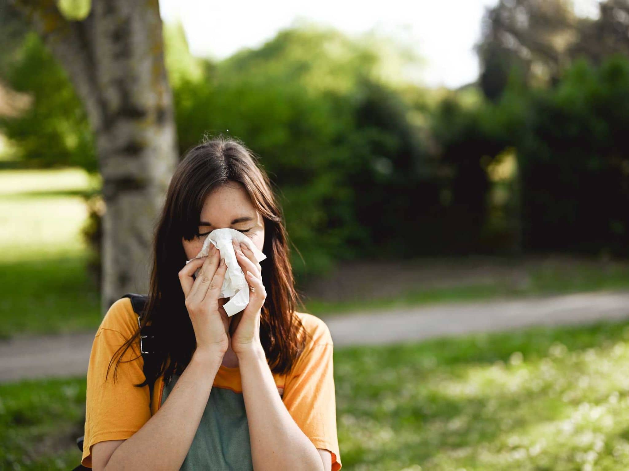 Sommergrippe: Junge Frau putzt sich die Nase
