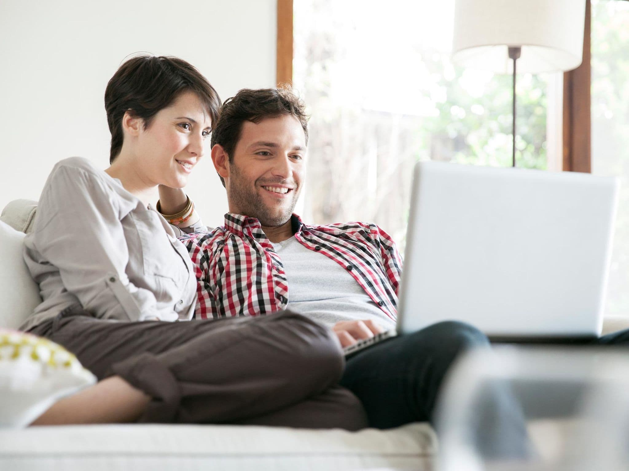 Qualitätstransparenzbericht 2025: Mann und Frau sitzen auf dem Sofa und schauen gemeinsam auf den Bildschirm eines Notebooks.